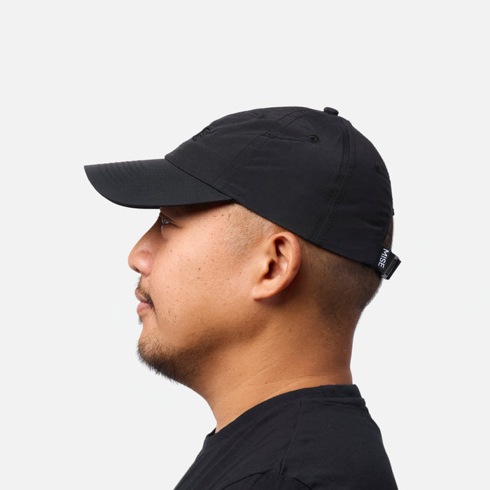The Dad Cap gallery position 1 side view showing black moisture-wicking 6-panel cap with MISE branded adjustable strap