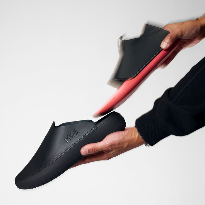 The MISE Relaxed 2 black chef shoe with red cushioned insole being removed by hand.