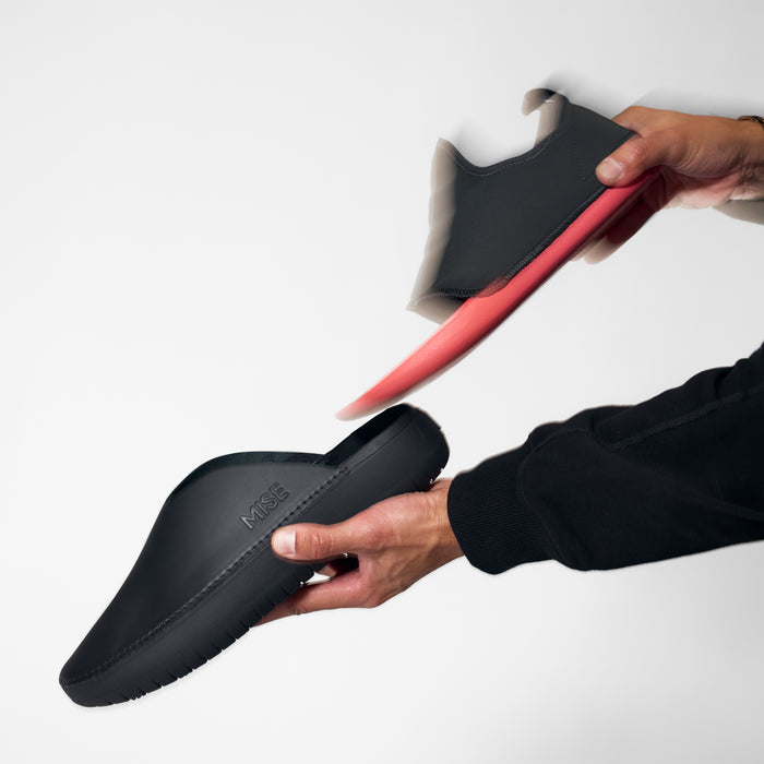 MISE Standard 2 black slip-resistant kitchen shoe insole being pulled out of exterior shell on light gray background