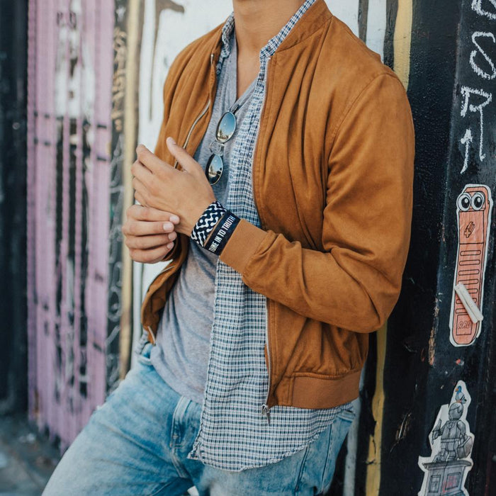 Lifestyle image of model resting against a wall and wearing two Tune In To Truth straps