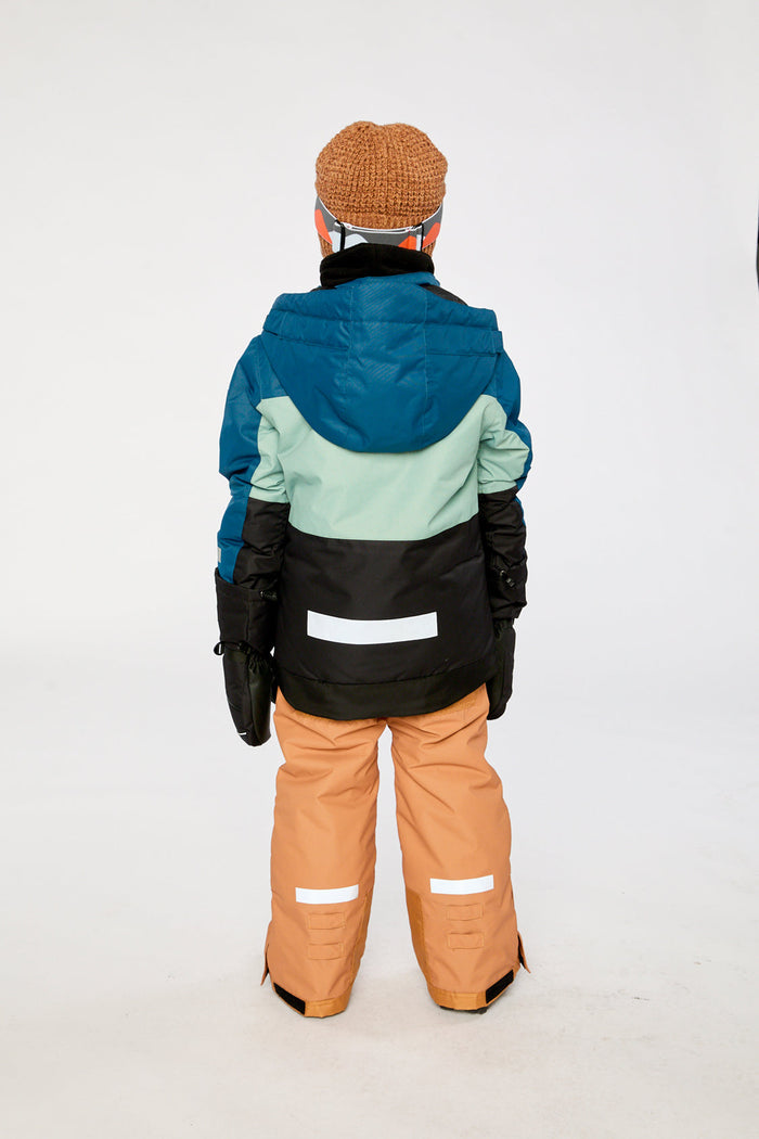 Child in the navy and tan TEKNIK snowsuit, back view