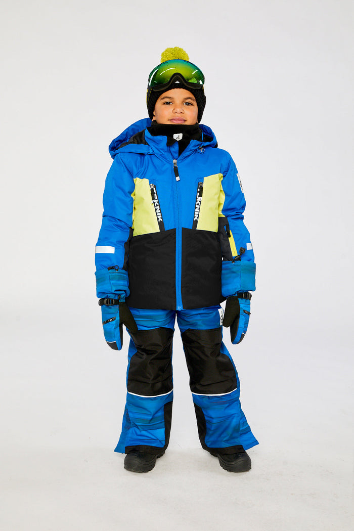 Child wearing the royal blue and yellow TEKNIK snowsuit with goggles, front view