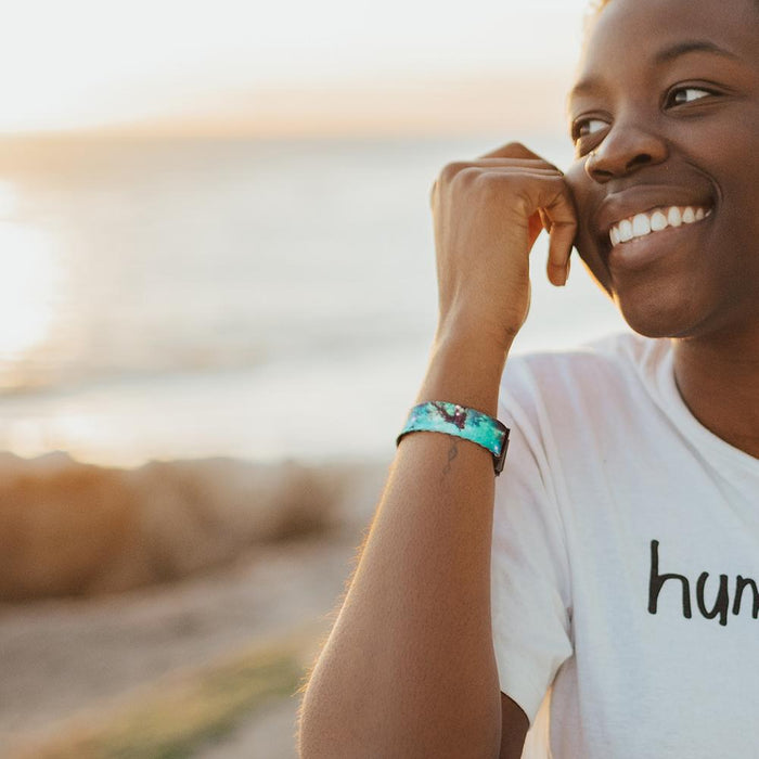 Lifestyle image of model smiling with the sun setting behind them and wearing Unbreakable