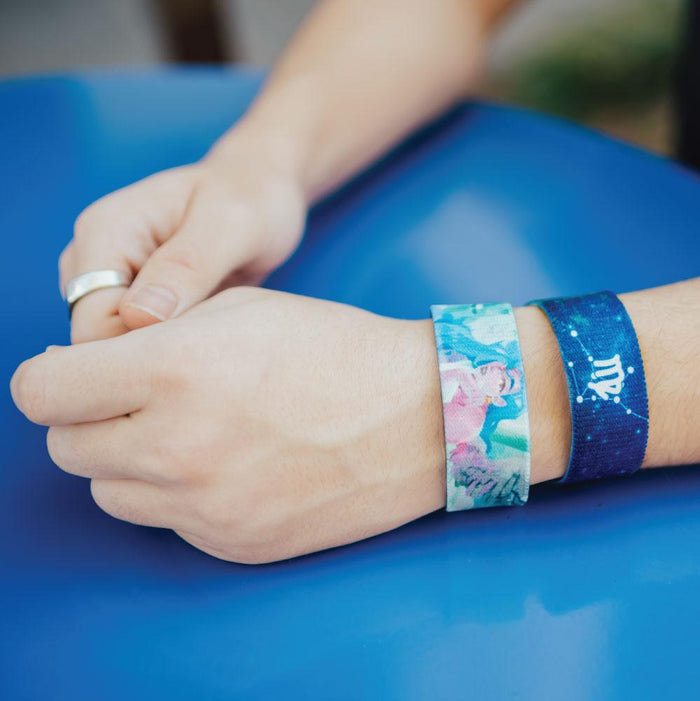 Lifestyle photo of models hands wear Virgo strap, one showing the angel and another showing Virgo symbol.
