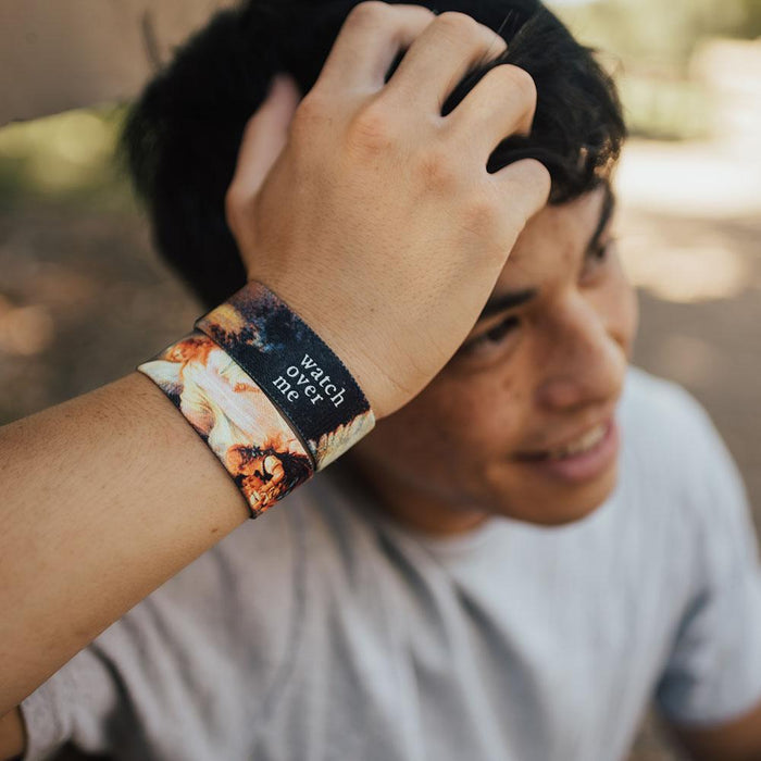 Lifestyle image close up of someone smiling with 2 Watch Over Me on their wrist