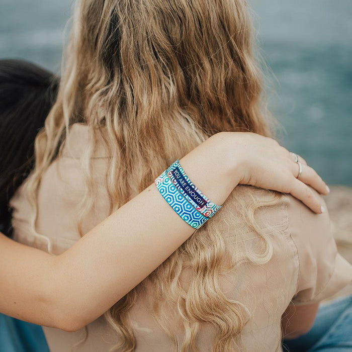 Lifestyle close up image of arm resting on shoulders of someone and wearing 2 You Are Enough